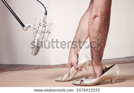 Caucassian soundman hands inside femail shoes imitating woman steps sounds front a professional studio microphone in a sound record professional studio. Full Color image. 