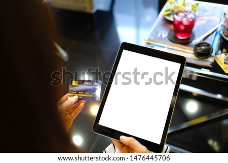 Close up of woman using blank tablet and credit card sending massages on the coffee shop.