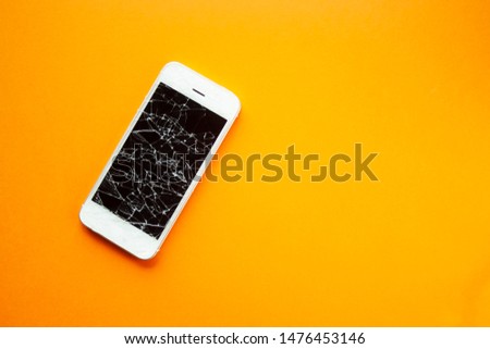Broken screen of smartphone on the orange background. Smashed glass of cell phone, illustration for repair, fix phone services. Top view with copyspace