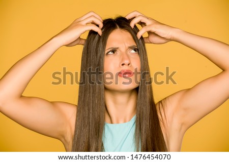Beautiful young woman with itchy scalp on yellow background