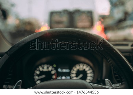 Inside view, hand of a driver on steering wheel of car with traffic jam on road background. High-quality free stock image of the steering wheel inside in rainy day. Drive in stormy day and bad weather