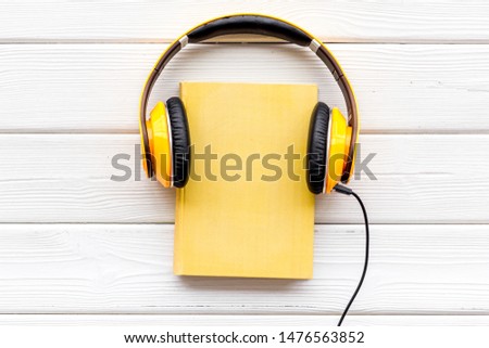 listen to audio books with headphone on white wooden background flatlay
