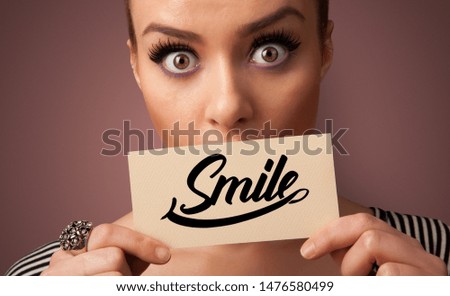 Person holding card with smile in front of her mouth
