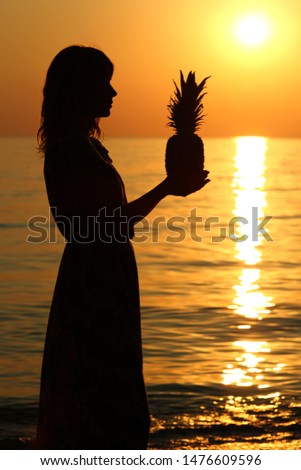 girls silhouette by the sea on summer with a pineapple