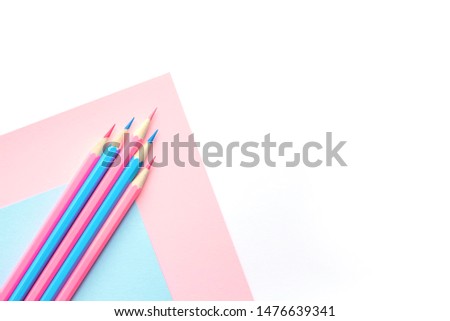  Pink and blue pencils and paper on white background. Top view, flat lay composition, frame, layout. Copy space for text or design.