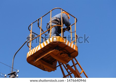Worker standing in bucket isolated on sky background. Horizontal color photography.
