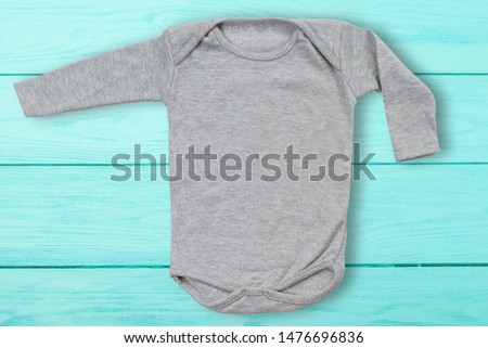 Gray baby mock up jumpsuit on blue wooden background. Baby bodysuit mockup and template blank copy space. Top Front view. One-piece newborn shirt clothes mock-up.