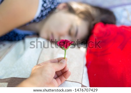 Good morning. The girl is sleeping, and her husband gives flowers a red rose and immediately takes a picture that she does not notice