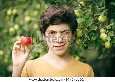teenager happy boy with apple smile wink on apple tree green garden background