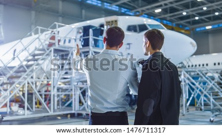 Aircraft Maintenance Worker and Engineer Having Conversation. Looking at the airplane.