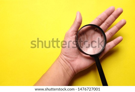copy space hand holding magnifying glass on the on a yellow background