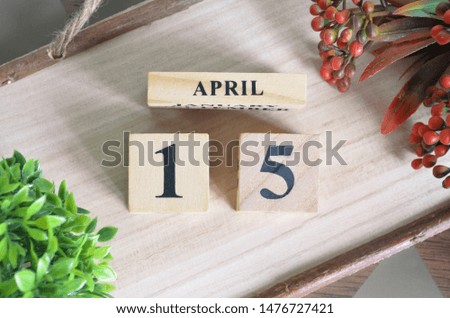 April 15. Date of April month. Number Cube with a flower and Sign wood on Diamond wood table for the background.