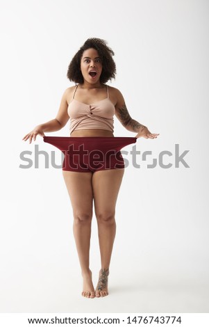 My shorts are too big. Cropped photo of young surprised lady stretching her panties with arms
