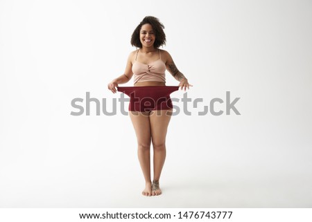 I lost some weight. Happy smiling young lady stretching her panties with arms in studio