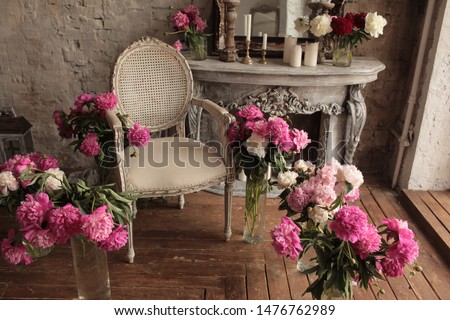 vintage armchair decorated with peonies  flowers and greens, stands in a classic room on wooden floor s near large window and gray fireplace