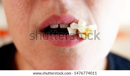 An Half open caucasian woman lips holding a popcorn on the right side of the lips