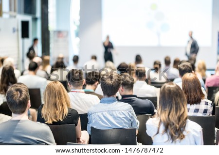 Business and entrepreneurship symposium. Speaker giving a talk at business meeting. Audience in conference hall. Rear view of unrecognized participant in audience. Royalty-Free Stock Photo #1476787472