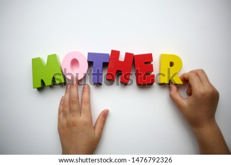 Hands showing mother a word made of wooden letters. Colorful letters of the alphabet the child holds in his hands. ABC game. Mother's day. Kids love mom
