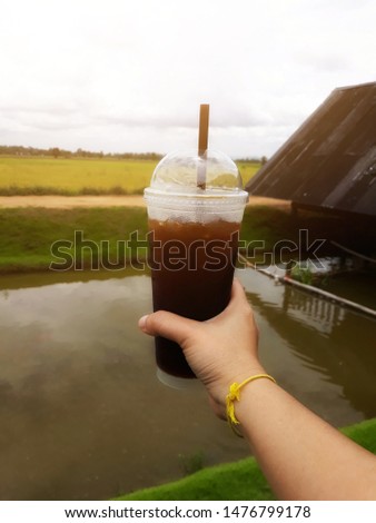 Close-up pictures of people holding a coffee cup  America cool glass plastic background rice fields sky  Holiday drink concept