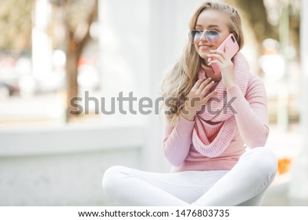 Attractive young woman talking on the cell phone outdoors. Female doing selfie.