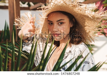 Photo of amazing young beautiful woman at the beach walking in a beautiful sunny morning over tropical plants.