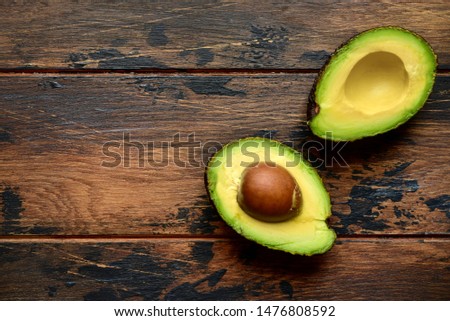 Halves of fresh raw avocado with baby spinach leaves on a dark wooden background Top view with copy space.