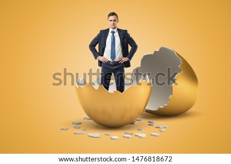 Young businessman standing in golden eggshell as if he just hatched out from egg. New business. Inexperienced businessmen. New ideas. Royalty-Free Stock Photo #1476818672