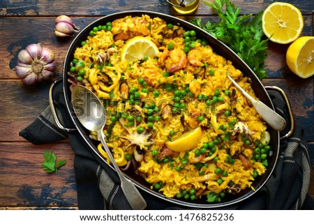 Classic valencian paella from rice with seafood and vegetables - traditional dish of spanish cuisine in a frying pan on a light slate, stone or concrete background.Top view with copy space.
