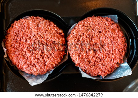 Flat top closeup of two raw uncooked red vegan plant based meat burger patties in packaging Royalty-Free Stock Photo #1476842279