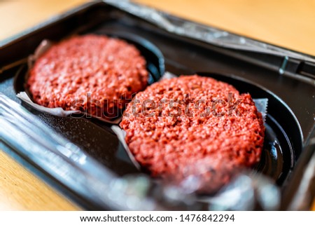 Closeup of two raw uncooked red vegan meat burger patties in plastic packaging Royalty-Free Stock Photo #1476842294