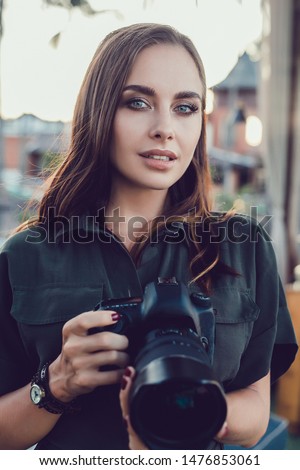 Fashion look, pretty cool young woman model with retro film camera wearing a elegant hat, brown jacket, curly hair outdoors over city grey background, happy smile, sunglasses, isolated wall, tan
Bali