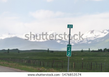 Gunnison to snowy Crested Butte mountain on highway road 135 in rural countryside with mile distance sign