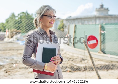 Portrait of business mature businesswoman on construction site repairing road in city, paving stone laying