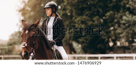 Young woman in special uniform and helmet riding horse. Equestrian sport - dressage. Royalty-Free Stock Photo #1476906929