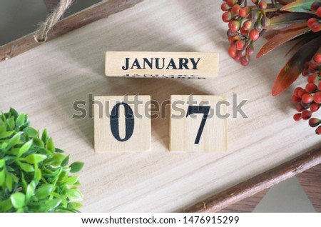 January 7. Date of January month. Number Cube with a flower and Sign wood on Diamond wood table for the background.