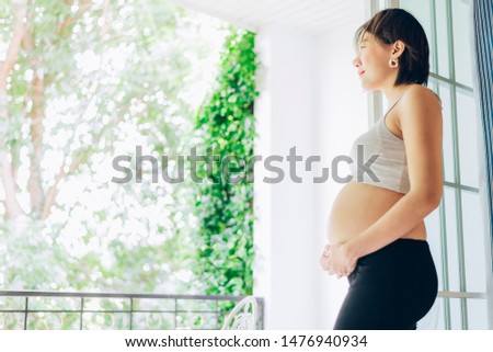 24 Weeks pregnant woman relaxing near window at home in bedroom