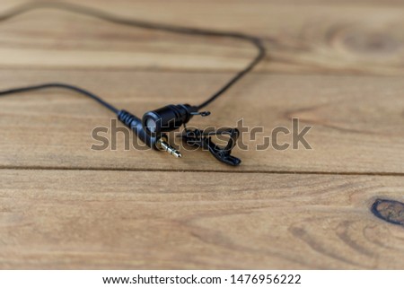 Lapel microphone with cable and clip on wooden table.