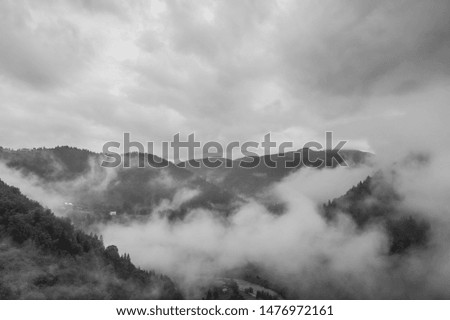 Aerial view of clouds and fog over mountains hills. Black and white