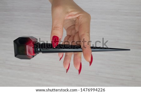 Female hand with long nails and a bottle with red nail polish