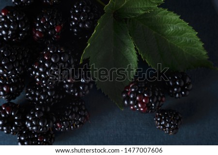 Fresh blackberries, close-ups on a dark background with a green leaf. Top view, flat lay