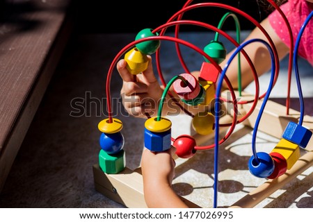 child playing with Bead Maze toy in kinder garden.Children's developing toy. The labyrinth of wooden beads. Kids learning colors, form and count.fine motor skills.