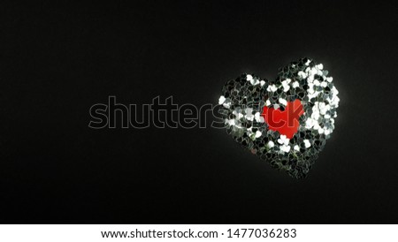 Decorative red hearts and silver confetti on a black background. Image for Valentine's day.Place for text.