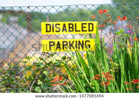 Disabled parking sign on car number plate on fence with flowers at garden centre