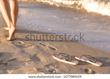 Closeup of woman and flip flops on sand near sea, space for text. Beach accessories