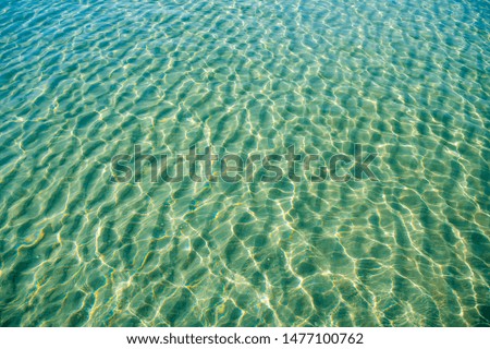 Tropical blue-green waters background in shallow seas with small waves in bright sunlight