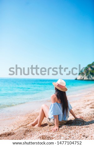 Young beautiful woman relaxing at empty pebble beach in natural reserve