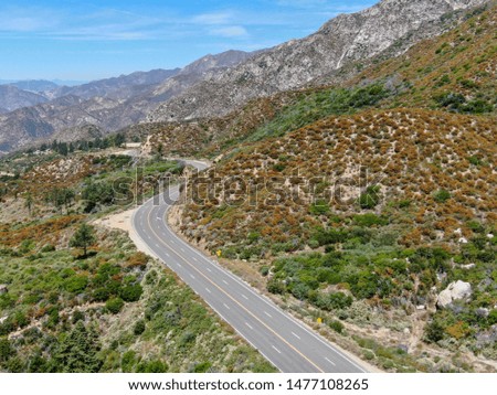 Asphalt road bends through Angeles National forests mountain, California, USA.
Thin road winds between a ridge of hills and mountains at high altitude