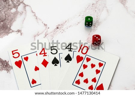hand of playing cards with two dice on a marble background