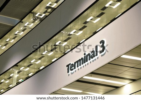 Black Terminal 3 sign in airport hall