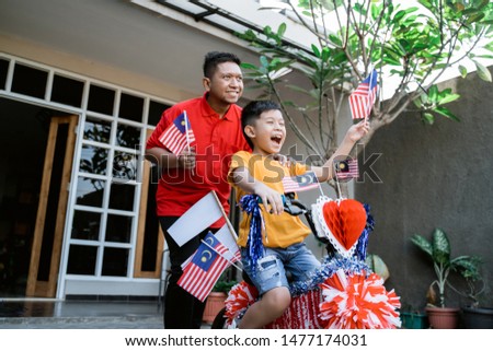 father and son with decorated bicycle and malaysia flag for independence day celebration
